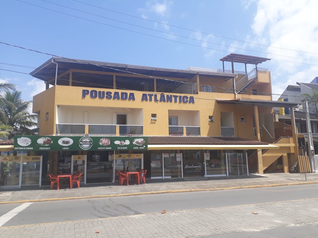 Foto da fachada da pousada com um carro na frente e uma placa escrito Pousada Atlantica